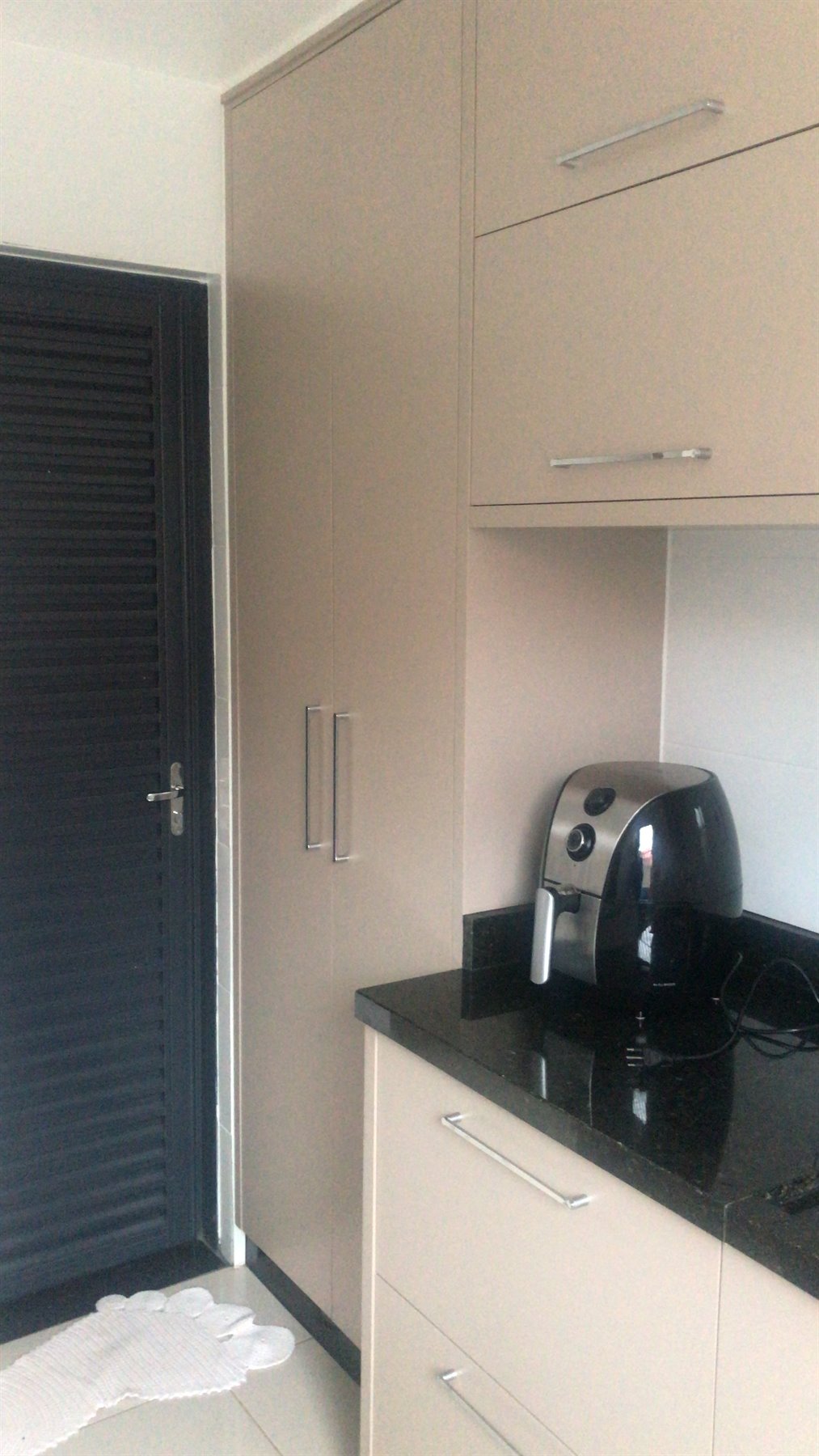 Cozinha planejada em tom fendi com granito preto