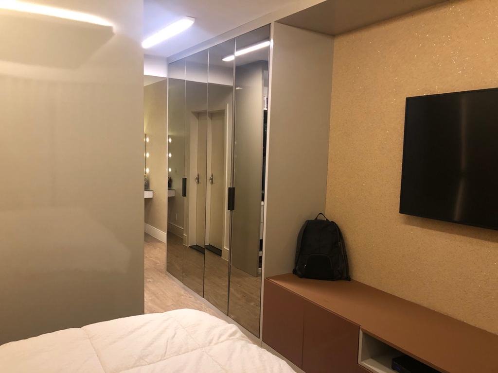 Dormitório com guarda-roupa espelhado e painel de TV planejado